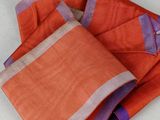 an orange and purple scarf with a gold bell hanging from it ' s end