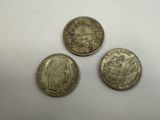 three silver coins sitting on top of a white surface