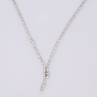 un collier en or blanc orné d'un pendentif en forme de croix sertie de diamants, sur fond blanc
