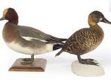 une paire de canards posés sur un socle en bois, sur une surface blanche
