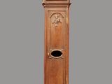 une grande horloge comtoise en bois sur un fond gris