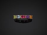 a multicolored sapphire and diamond ring on a black background