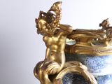 a blue and white vase with a gold statue on it