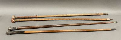 four old wooden canes are lined up on a gray surface