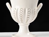 a white vase sitting on a table with a black background