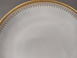 a white plate with a gold rim on a table
