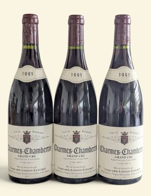 three bottles of red wine are lined up on a white surface