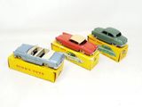 three toy cars are sitting on top of boxes on a white surface