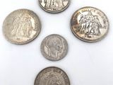 five different coins are arranged in a circle on a white surface