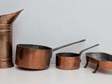 many different types of copper pots and pans on the table
