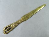 a gold spoon with a gold handle on a white surface