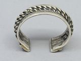 a close up of a silver ring with a braid design