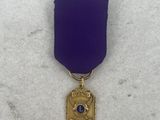 a close up of a purple ribbon with a gold medal on it
