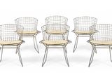 six wire chairs with wooden seat pads on a white background
