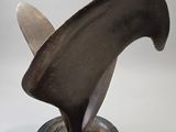 une sculpture métallique représentant un aileron de requin, posée sur un socle