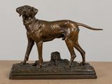 bronze statue of a dog standing on top of a wooden base