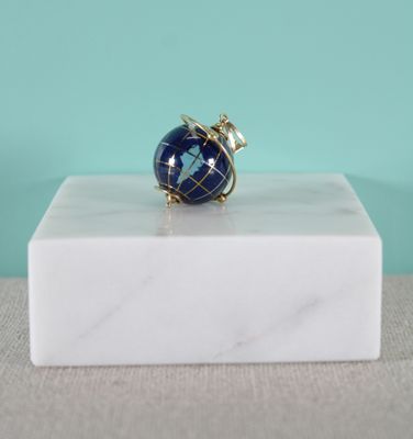 un gros plan d'une bague posée sur un bloc de marbre, sur fond bleu
