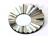 un miroir rond orné de nombreux miroirs, posé sur une surface blanche