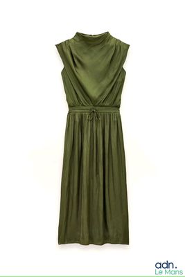 the green dress is hanging on a hanger on the wall