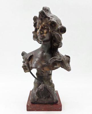 un buste en bronze représentant une femme tenant un oiseau, posé sur un socle en bois