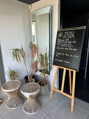 a chalk board with a menu written on it in front of some plants