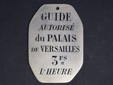 silver plate with the words guide autorise du palais de versailles 75°s l ' heure written on it