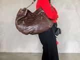 a woman holding a large brown purse in a room