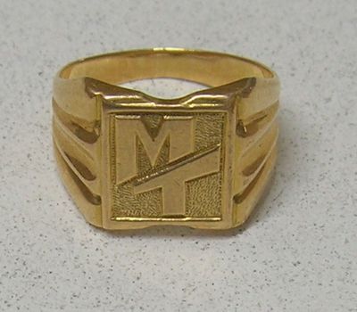 une photo d'une bague en or sur laquelle figure la lettre « m »