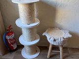a cat tree and a stool next to a wall