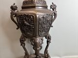 a bronze urn with a bird on top of it