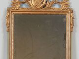 a mirror with a gold frame on a shelf