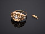 une bague en or sertie d'un diamant, posée sur un fond noir