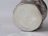 a silver cup that is sitting on a white surface