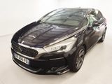 Une voiture noire est garée dans une pièce blanche au sol blanc.