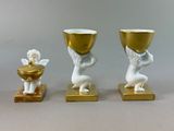 three statues of angels holding cups and a gold bowl