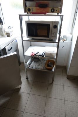 un micro-ondes posé sur une étagère dans une cuisine, près d'une fenêtre