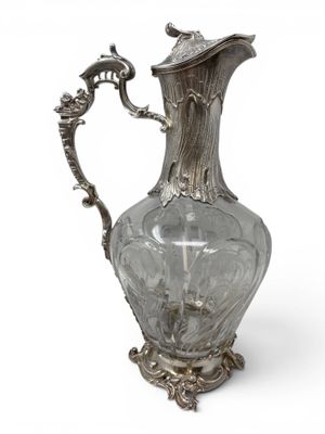 an antique silver plated glass pitcher on a stand with a handle