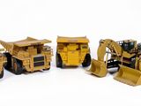 quatre engins de chantier miniatures posés les uns à côté des autres