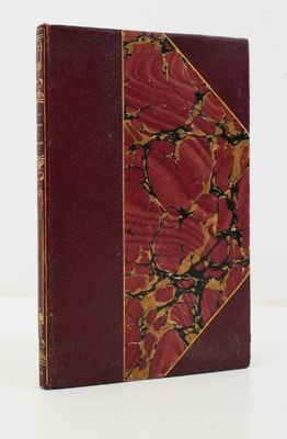 un vieux livre à la couverture rouge posé sur une surface blanche