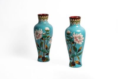 une paire de vases bleus ornés de fleurs roses sur fond blanc