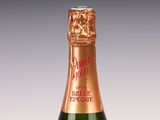 Des bouteilles de champagne sont disposées sur une surface blanche avec un fond gris.