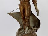 une statue d'un homme tenant une horloge au-dessus d'une table