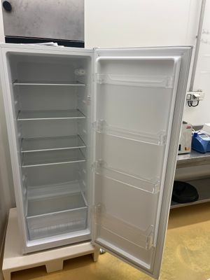 un réfrigérateur blanc dont la porte est ouverte, dans une pièce