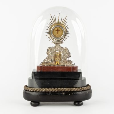 une horloge posée sur un socle, sous un dôme en verre