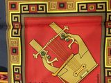 a picture of a red and gold scarf with a picture of a musical instrument on it