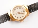 a gold wrist watch with a black strap on a white surface