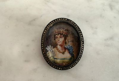 une petite image représentant une femme en robe, posée sur une table