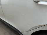 a white car that has a dent in the side of it