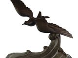 bronze sculpture of a bird on a wave on a marble base