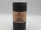 a black candle with a brown label on it sitting on a white surface